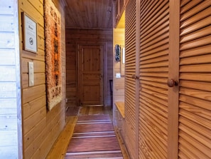 Un pasillo de madera con alfombra a rayas, una puerta con contraventanas de madera y un letrero en la pared.