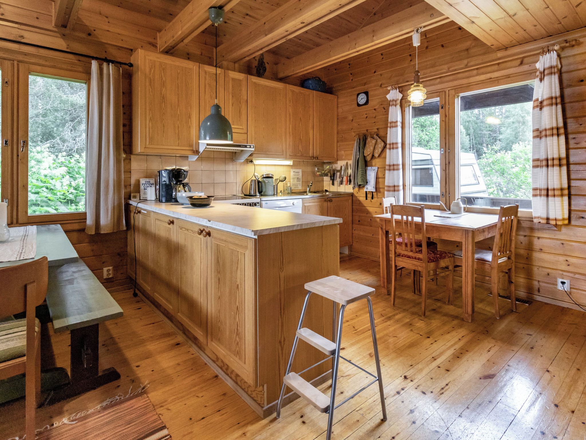 A wooden cabin interior with a kitchen, dining area, and a small bar.