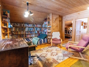 Una habitación acogedora con estanterías de madera, un escritorio, dos sillas y una alfombra estampada.