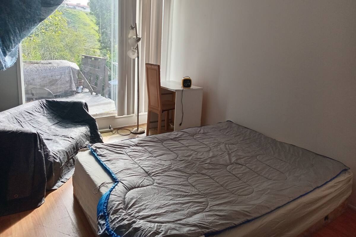 Une chambre à coucher avec un lit, une chaise, un bureau et une fenêtre avec des rideaux.