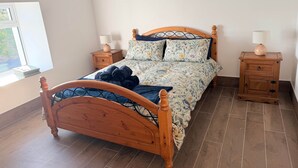 Un letto di legno con copripiumino floreale, due comodini con lampade e una finestra che si affaccia sul verde.