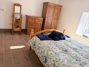 A bedroom with a bed, wooden wardrobe, and a mirror.
