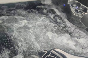 Una bañera de hidromasaje con burbujas y vapor visibles, lo que indica que está en uso.