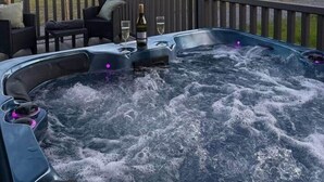 Un jacuzzi con vistas al paisaje, mobiliario exterior y una terraza de madera.