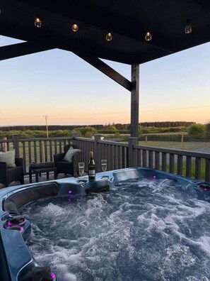 Un jacuzzi con vistas al paisaje, mobiliario exterior y una terraza de madera.