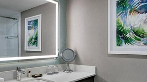 Une salle de bain moderne avec un grand miroir, un lavabo et un tableau encadré accroché au mur.