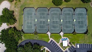 Vue aérienne d’un complexe de tennis comprenant plusieurs courts, un parking et des espaces verts environnants.