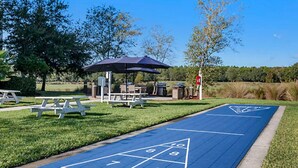 Una cancha de shuffleboard azul con mesas de picnic y una sombrilla.