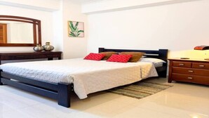 A bedroom with a bed, a dresser, a mirror, and a wall-mounted plant.