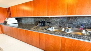 A kitchen with wooden cabinets, a granite countertop, a coffee maker, and a sink.