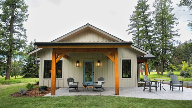 Een huis met een overdekte veranda, twee stoelen, een tafel en een deur.