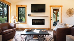 Een woonkamer met een open haard, een televisie en twee leren banken.