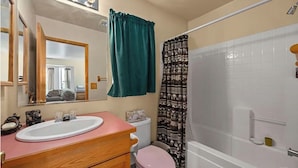 Un baño con lavamanos, espejo, inodoro y ducha.