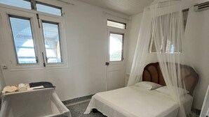 Un dormitori amb un llit, una finestra, una porta i un safataixa.