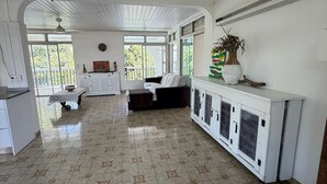 Una habitació àmplia amb terra de rajola, un sofà, una taula de dinar i un armari amb unitats de aire condicionat.