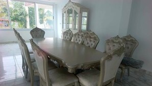 A dining room with a large table and ornate chairs, a cabinet, and a view of the outdoors. - LA BAIE DE MAERAPH by La Kopell (Assinie)
