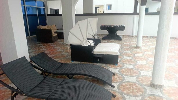A covered outdoor seating area with lounge chairs and a table with a canopy. - LA BAIE DE MAERAPH by La Kopell (Assinie)