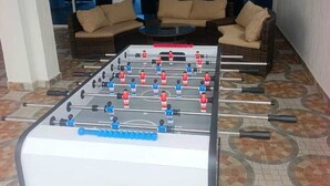 A foosball table in a room with patterned flooring, two sofas, and a view through large windows. - LA BAIE DE MAERAPH by La Kopell (Assinie)