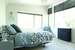 Un dormitorio con cama, cómoda, ventana y un cuadro en la pared.