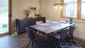 A dining area with a large table, chairs, a cabinet, and a hanging light fixture.