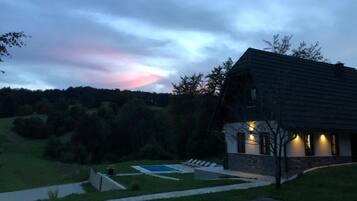 Uma casa com telhado inclinado, piscina e um caminho pavimentado que leva à entrada.