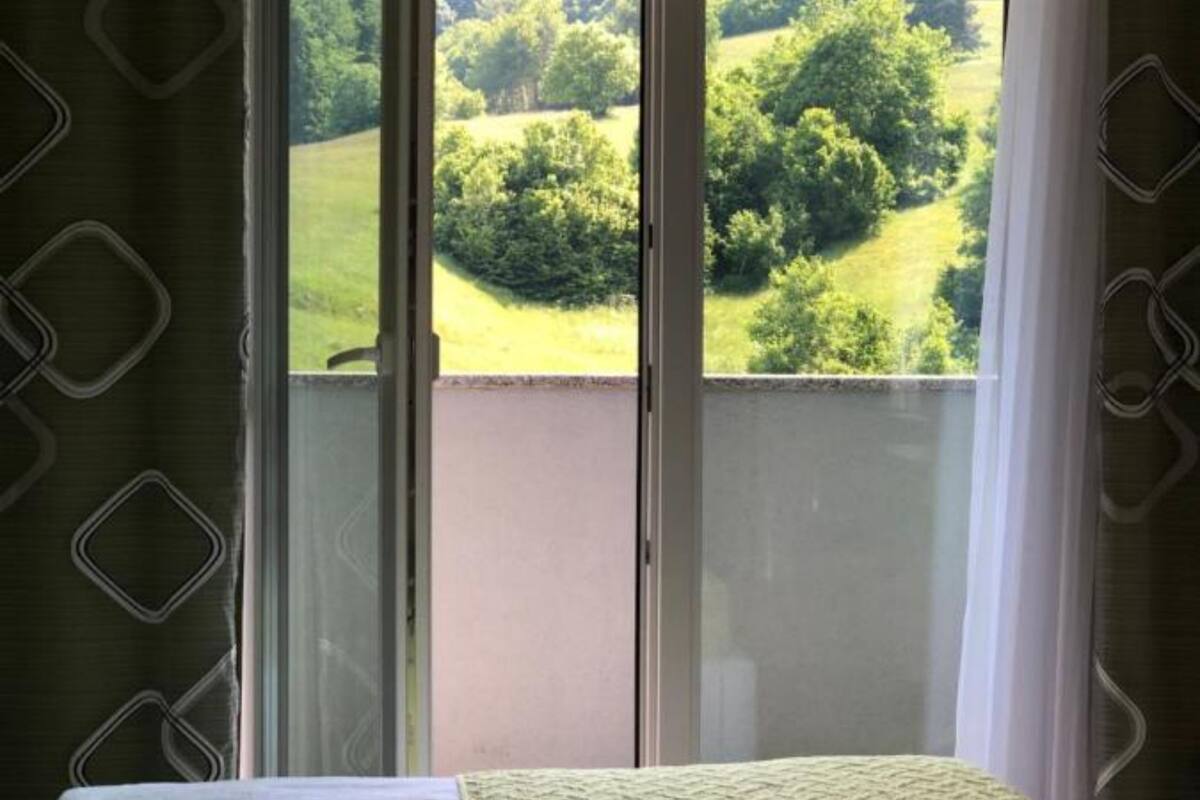 Una habitación con balcón, cama y vistas a un paisaje verde.