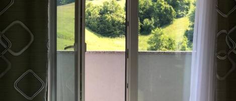 Una habitación con balcón, cama y vistas a un paisaje verde.