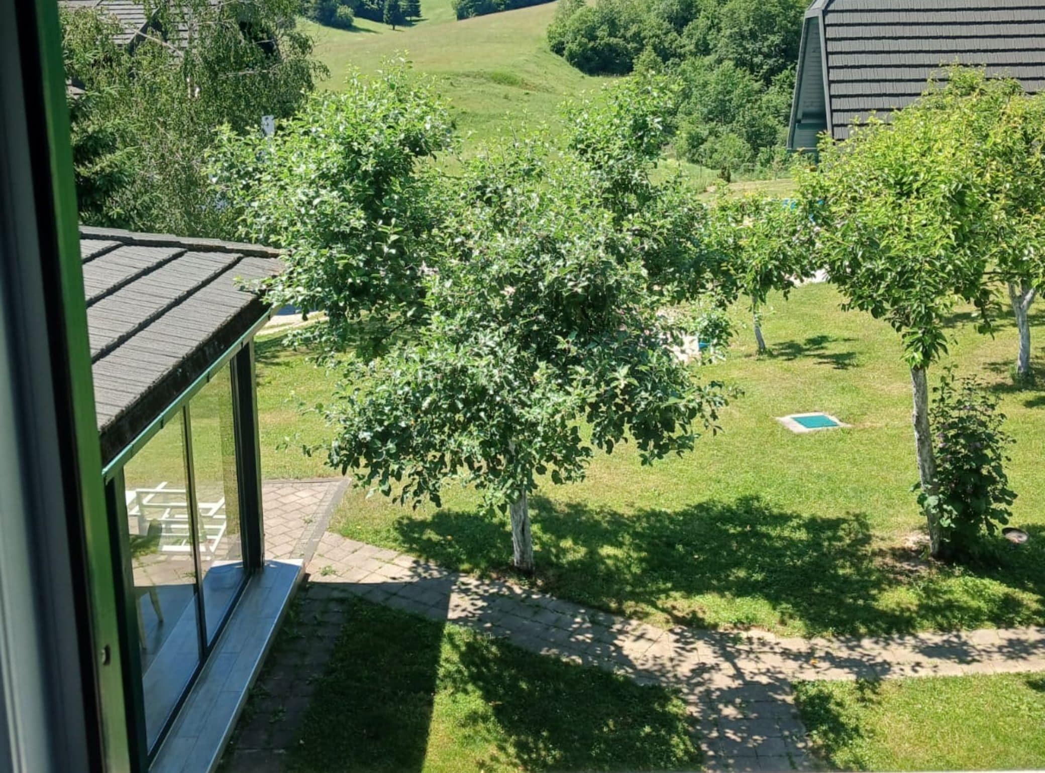 Vista de una zona residencial con una casa, césped y un pequeño estanque.