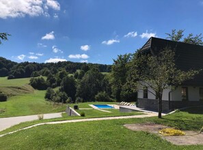 Une maison avec une piscine, entourée d’une pelouse verdoyante et d’arbres.