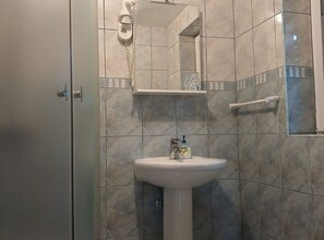 Une salle de bain équipée d’un lavabo, d’un miroir, d’un téléphone et d’un porte-serviettes.