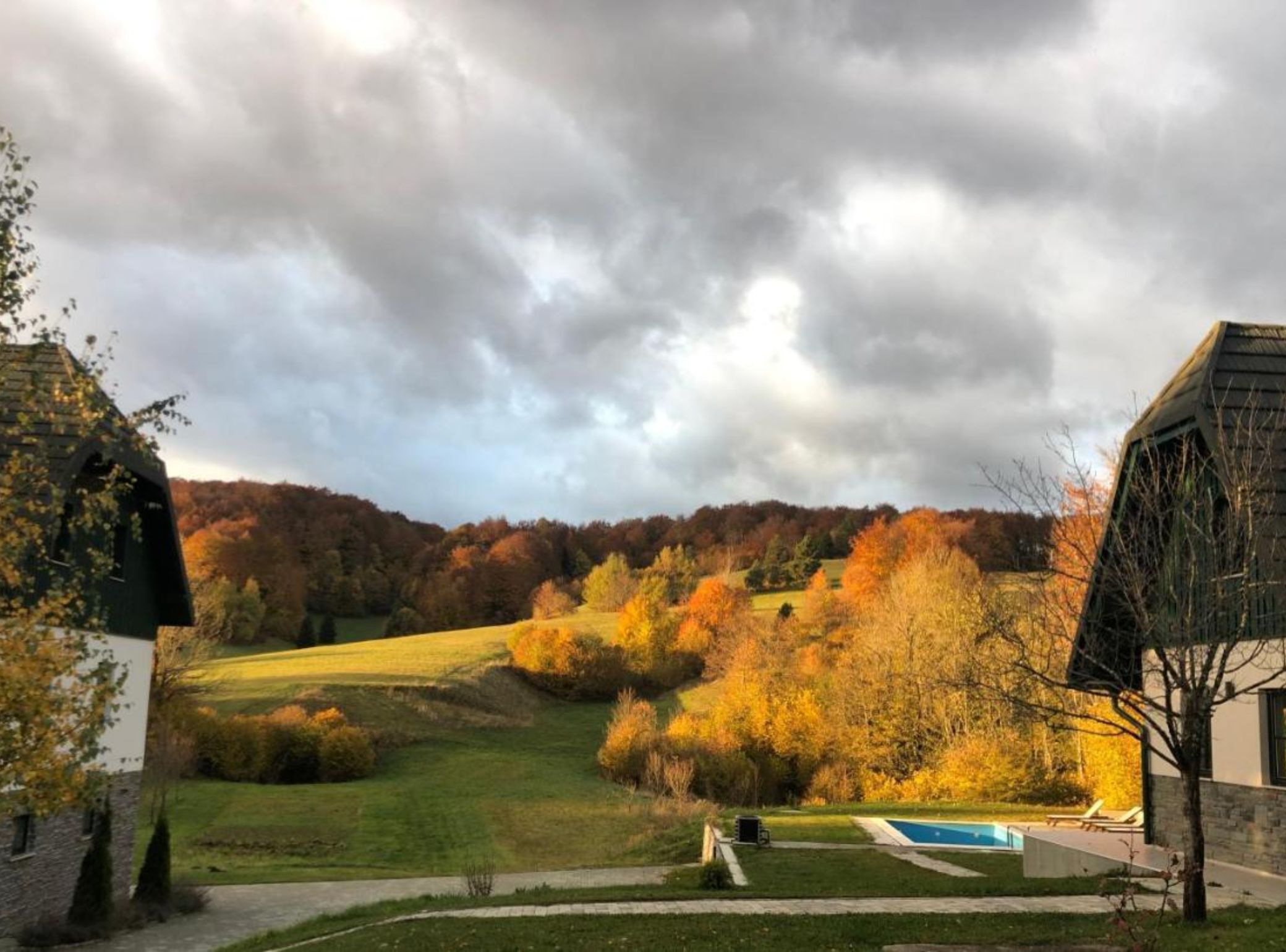 Et boligområde med swimmingpool, græsplæne og træer med efterårsfarver.