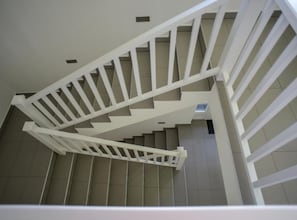 Una escalera en espiral blanca con barandilla, que conduce a un piso superior.