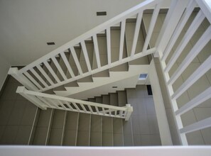 Una escalera en espiral blanca con barandilla, que conduce a un piso superior.