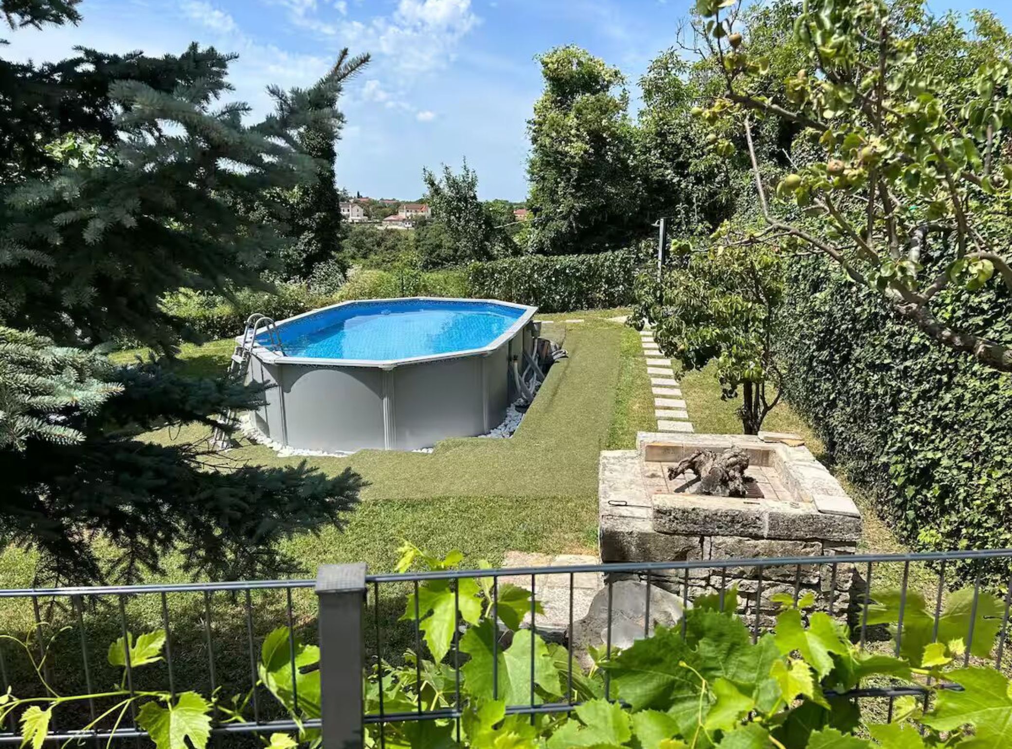 An outdoor swimming pool surrounded by a well-maintained lawn and various trees.