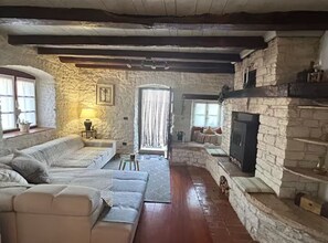 A rustic stone interior with a fireplace, a sofa, and a window. - Istrian Private Garden Oasis (Zminj)