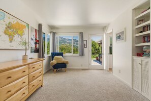 Ein Zimmer mit einem Holzkasten, einem blauen Sessel, einer Karte an der Wand und einem Bücherregal.