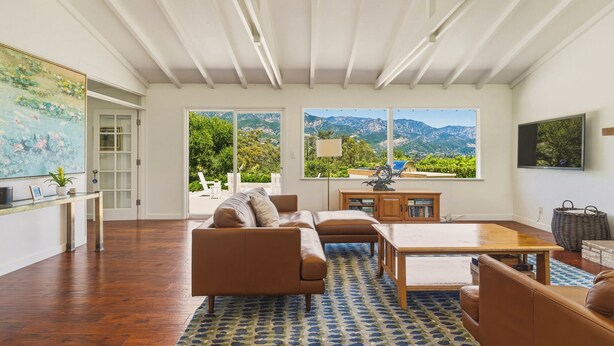 Ein geräumiges Wohnzimmer mit großem Fenster, einer Couch, einem Couchtisch und Bergblick.