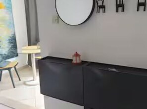 A modern room with a black console table, a round mirror, and a small red lantern.