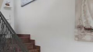 A staircase with a railing, a wall-mounted picture of a sailboat, and a small shelf with a decorative item.