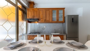 A modern kitchen with wooden cabinets, a stainless steel refrigerator, and a dining table set for six. - A.m. Apartments (Vrsar)