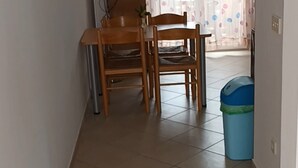 Um corredor com duas cadeiras de madeira, um cesto de lixo azul e piso de azulejos.