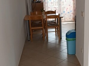 A hallway with two wooden chairs, a blue trash bin, and a tiled floor. - Apartments Cvetnić (Povljana)