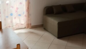 Um quarto com sofá, mesa e cortina estampada.