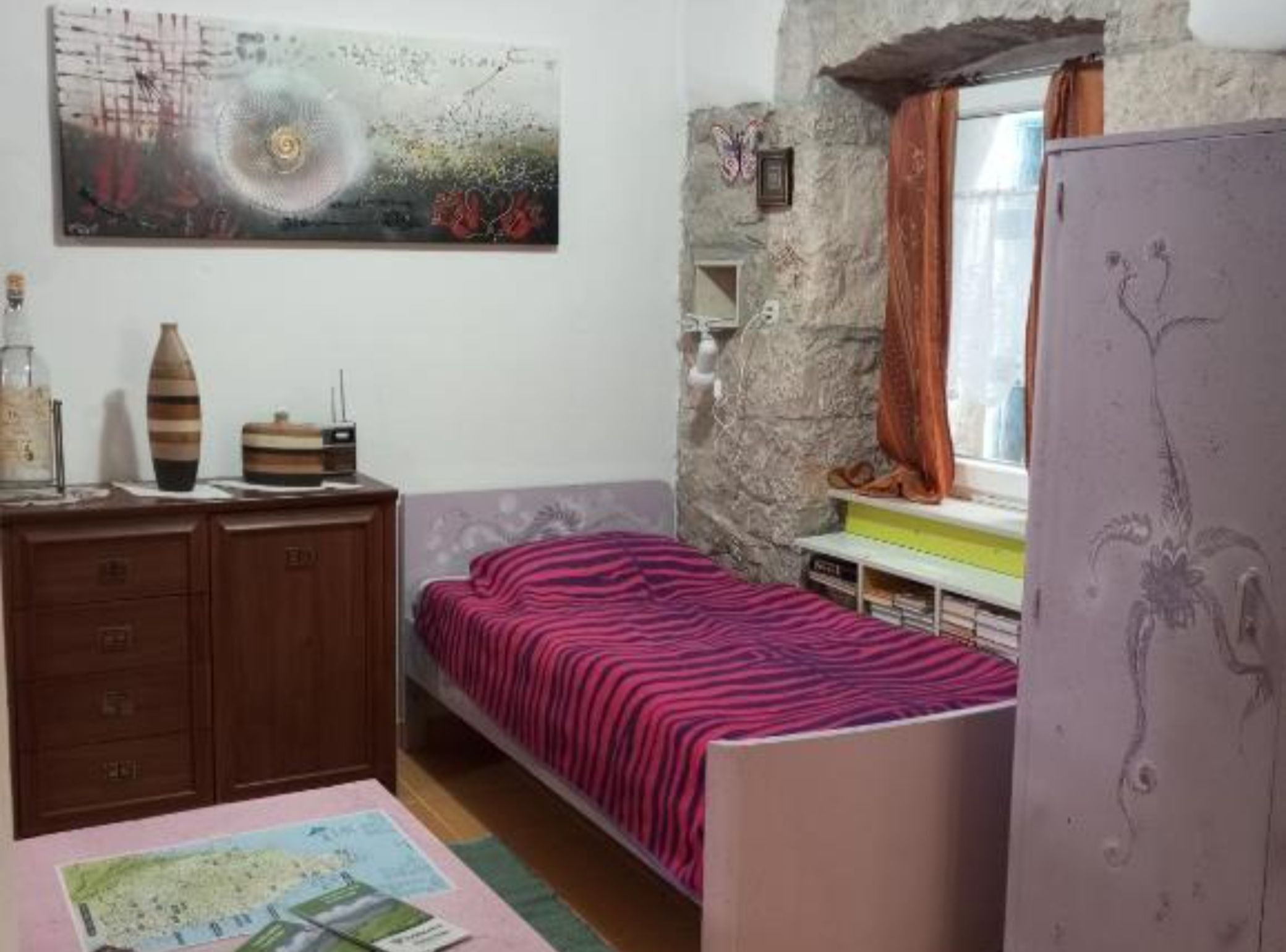 A bedroom with a bed, dresser, and a painting on the wall.