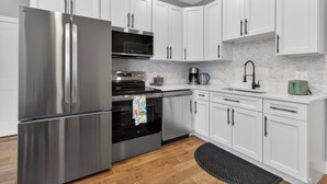 Una cocina moderna con electrodomésticos de acero inoxidable, armarios blancos y un salpicadero de mármol.