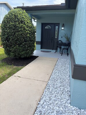 A house with a dark front door, a small porch with two chairs, and a large bush in the front yard. - Hide Away at Winter Park (Winter Park)
