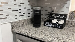 Een keuken met een koffiezetapparaat, een bordje voor een koffiebar en een granieten aanrecht.