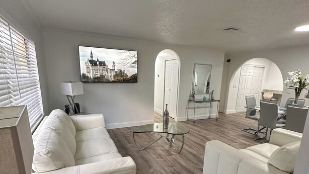 Een moderne woonkamer met een glazen salontafel, witte leren banken en een eethoek met een glazen tafel.
