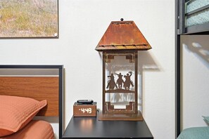 A bedside table with a clock, a decorative metal lantern, and a cushion. - Long Live Cowboys!  3-Bed 2-Bath Near ACU and Expo (Abilene)