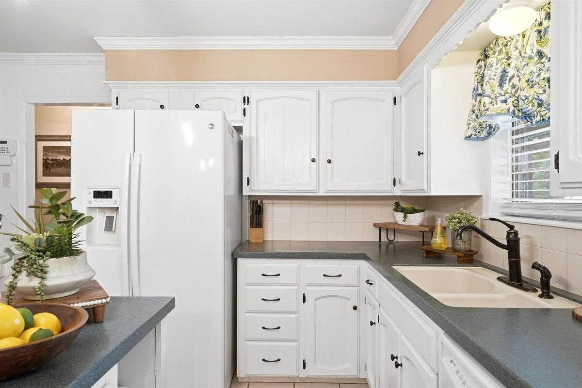 A kitchen with white cabinets, a double sink, and a refrigerator.